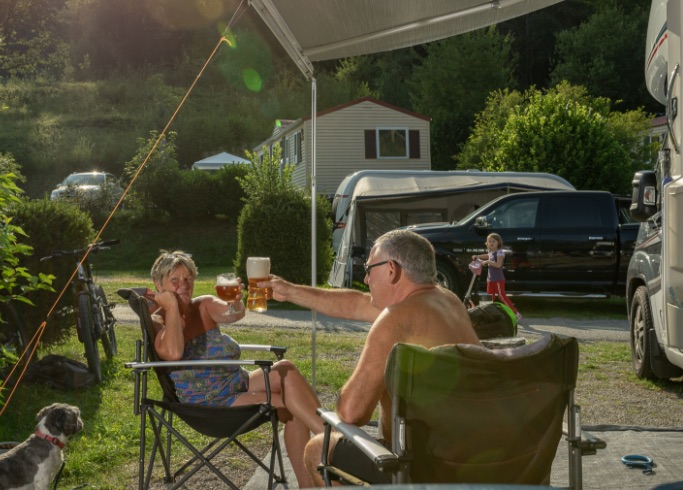 Campinggäste stoßen vor ihrem Wohnmobil Stellplatz mit Getränken an
